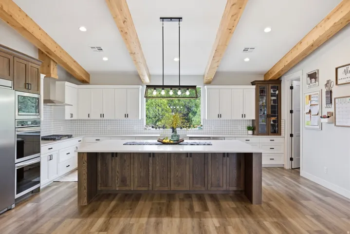 Dual tone kitchen featuring a kitchen island, decorative backsplash, recessed lighting, two tone color scheme, and light stone counters