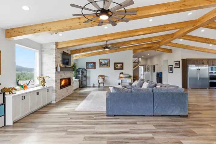 Living room with recessed lighting, light wood finished floors, a fireplace, vaulted ceiling, and a ceiling fan