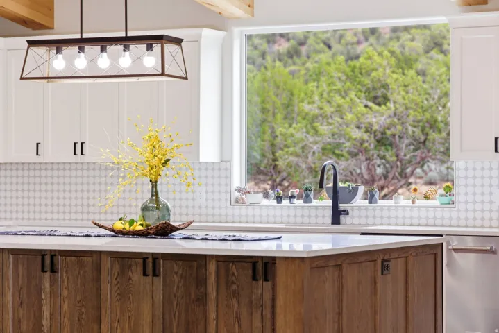 Kitchen with light stone countertops, tasteful backsplash, white cabinetry, and healthy amount of natural light