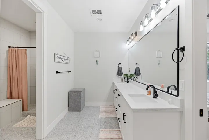 Full bathroom featuring double vanity and a shower stall