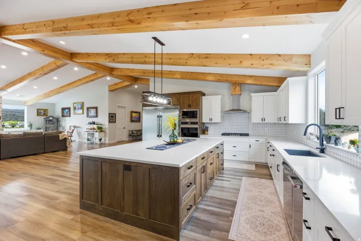 Dual tone kitchen with two tone cabinetry, plenty of natural light, a center island, open floor plan, and built in appliances