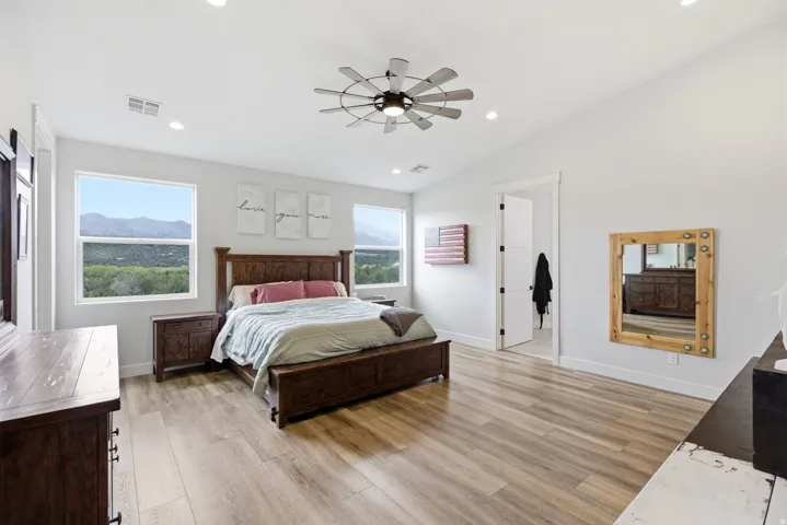Bedroom featuring light wood-style flooring, vaulted ceiling, a ceiling fan, recessed lighting, and a mountain view