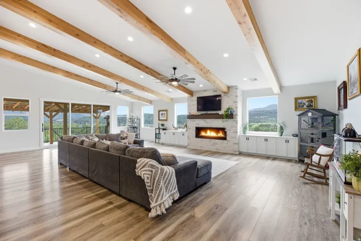 Living room featuring recessed lighting, light wood finished floors, beamed ceiling, a fireplace, and a ceiling fan