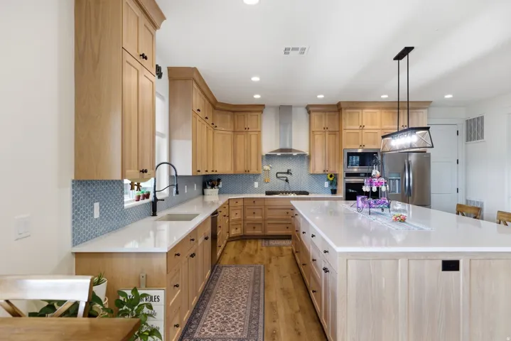 Kitchen with light wood finish cabinetry, a center island, stainless steel appliances, light stone counters, and a breakfast bar area
