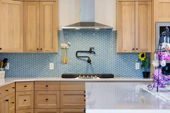 Kitchen featuring light stone countertops, tasteful backsplash, light wood finish cabinetry, and stainless steel gas cooktop