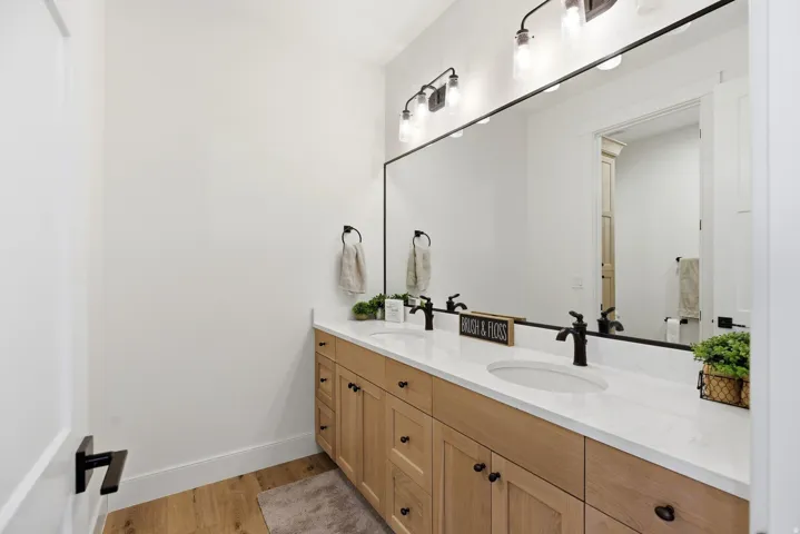 Full bath with double vanity and light wood finished floors