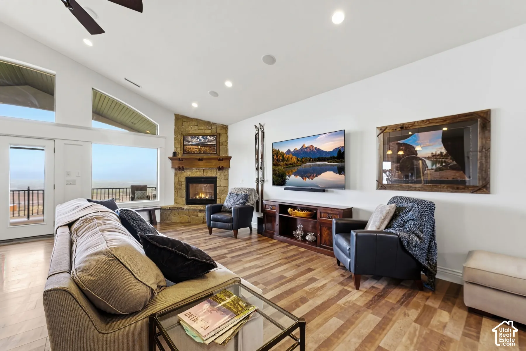 Living area with lofted ceiling, a stone fireplace, a ceiling fan, recessed lighting, and light wood-style floors