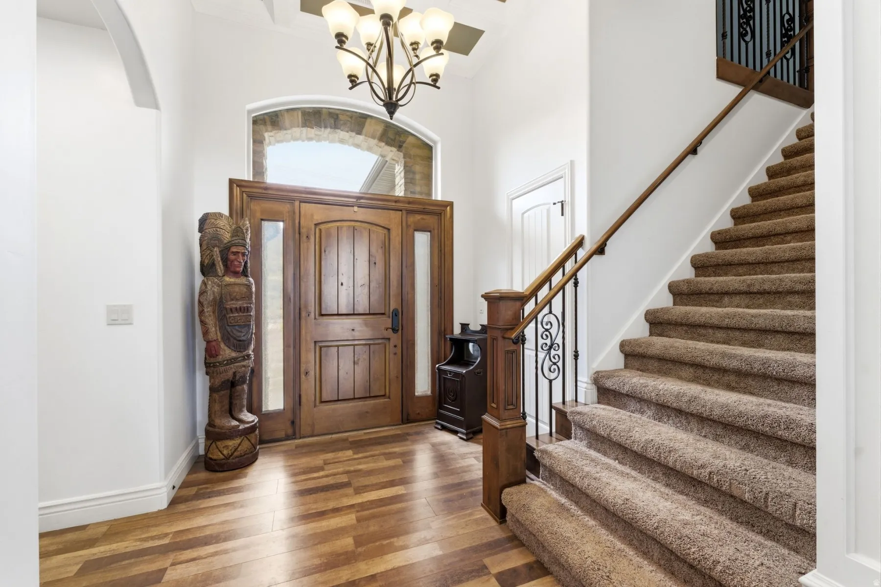 Foyer entrance featuring hardwood / wood-style floors, a chandelier, a high ceiling, and arched walkways