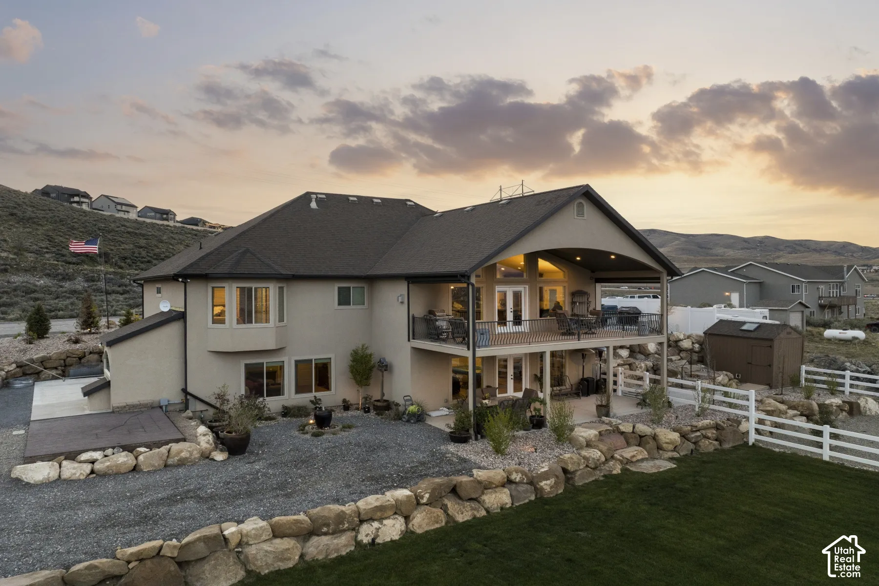 Back of house at dusk featuring a balcony, a storage unit, stucco siding, and a patio