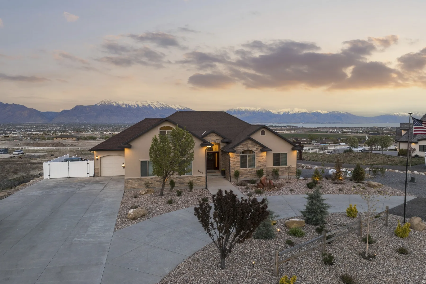 French country home with stucco siding, stone siding, a mountain view, a garage, and driveway