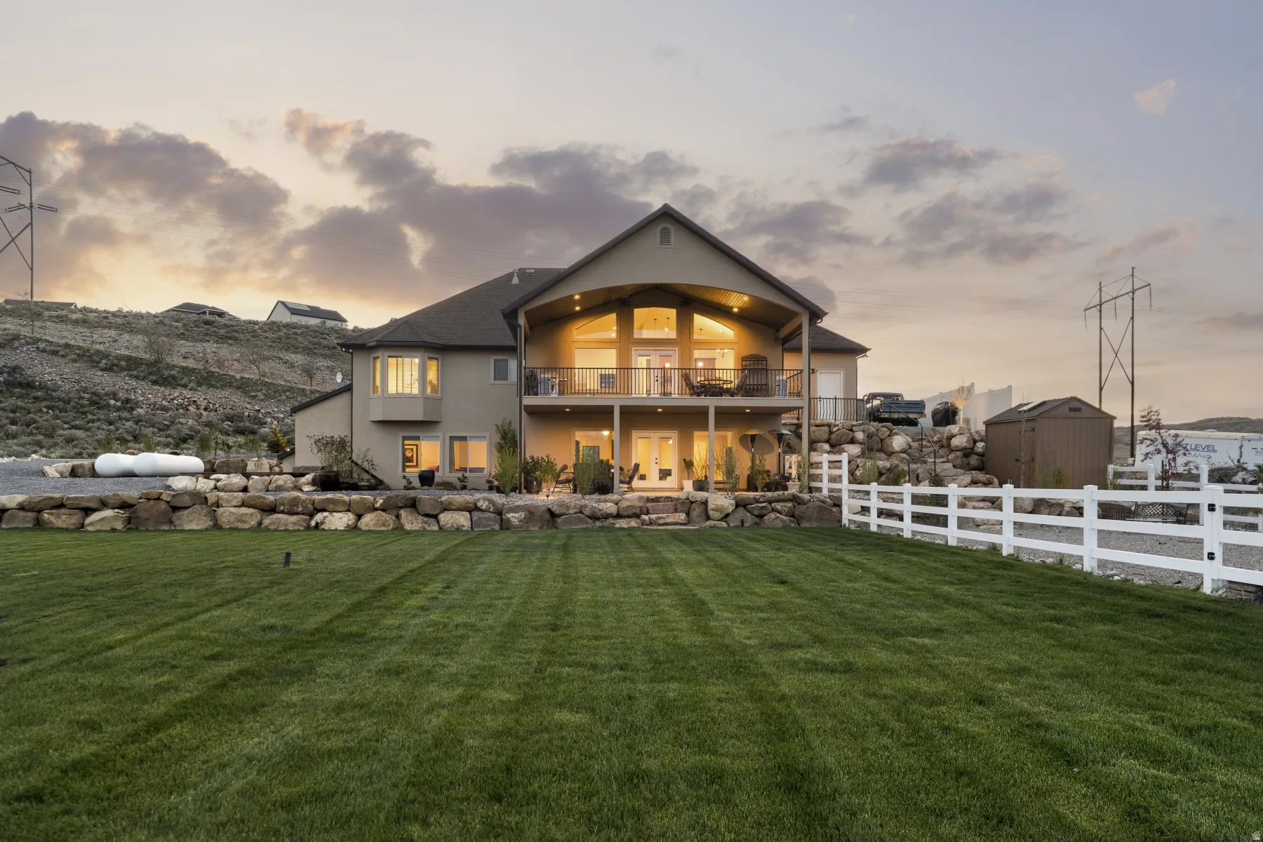 Back of house at dusk featuring stucco siding and a balcony