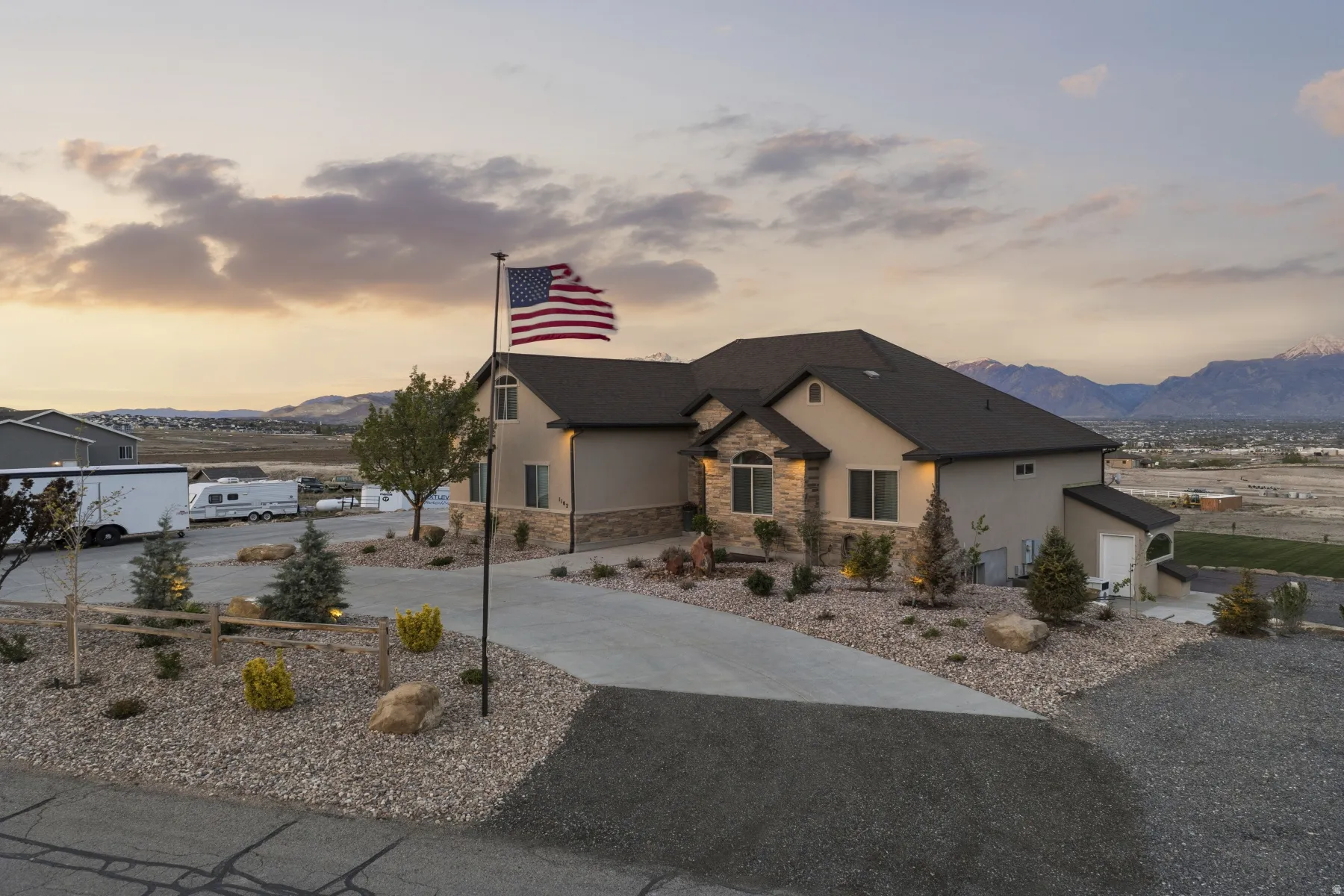 View of front of property with stone siding, stucco siding, driveway, and a mountain view
