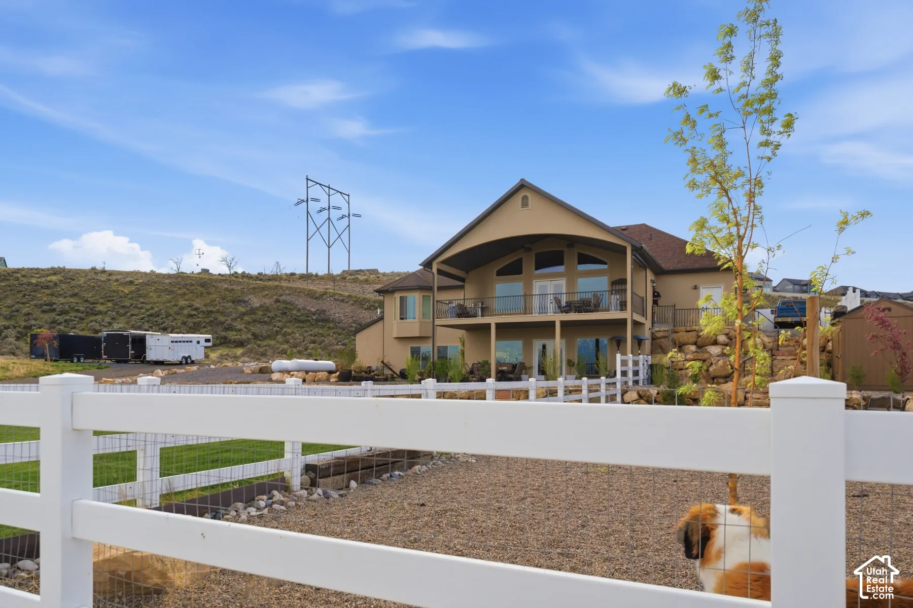 Rear view of house featuring a fenced backyard, stucco siding, and a balcony