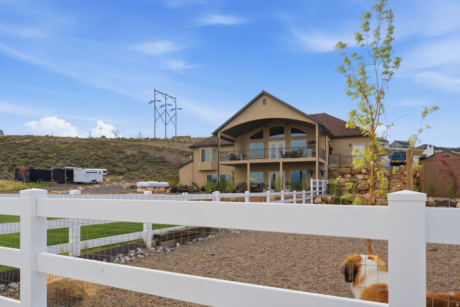 Rear view of house featuring a fenced backyard, stucco siding, and a balcony
