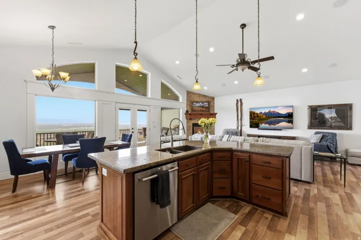Kitchen featuring a kitchen island with sink, open floor plan, dishwasher, dark stone counters, and light wood finished floors