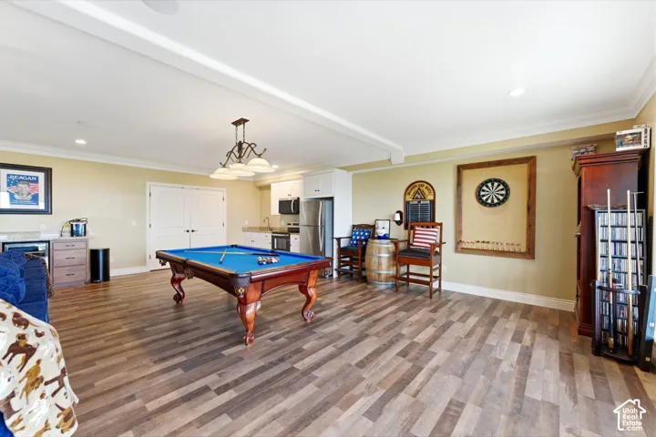 Game room featuring pool table, dark wood-type flooring, crown molding, recessed lighting, and bar