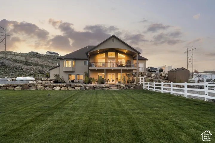 Back of house at dusk featuring stucco siding and a balcony