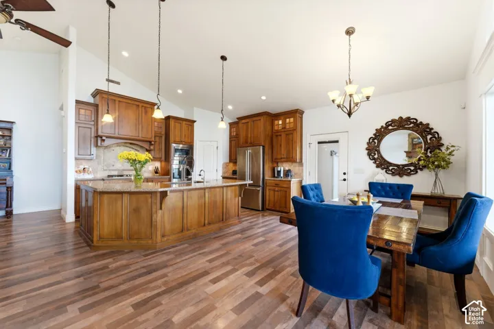Dining area featuring a chandelier, a ceiling fan, lofted ceiling, and dark wood finished floors