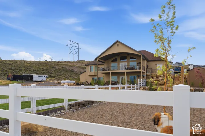Rear view of house featuring a fenced backyard, stucco siding, and a balcony