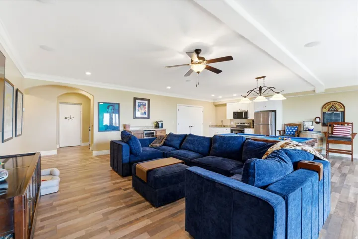 Living area with arched walkways, crown molding, light wood finished floors, a ceiling fan, and recessed lighting
