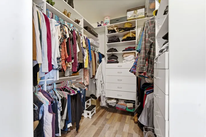Primary suite Walk in closet with light wood-style flooring