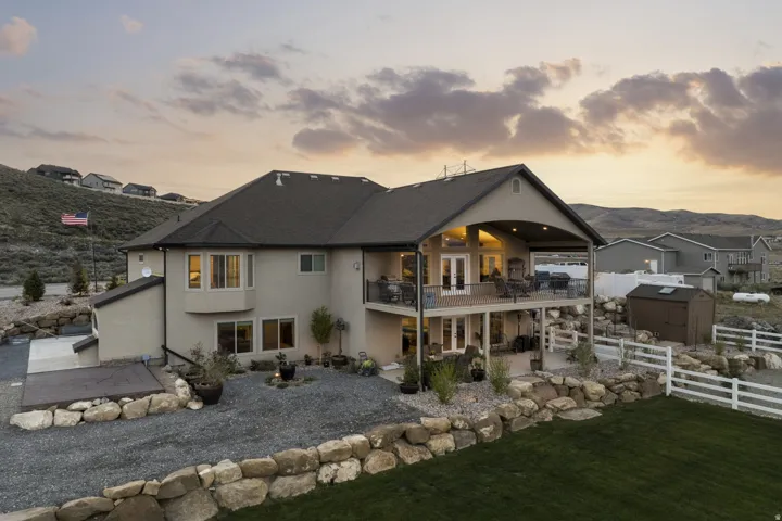 Back of house at dusk featuring a balcony, a storage unit, stucco siding, and a patio