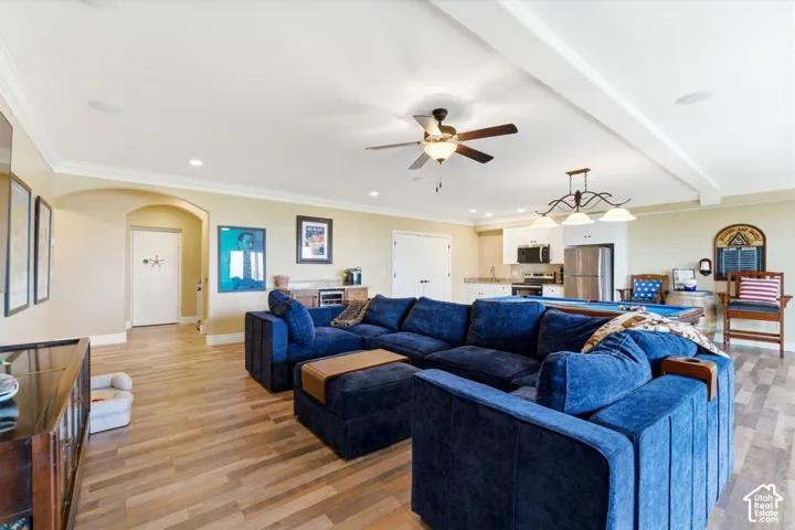 Living area with arched walkways, crown molding, light wood finished floors, a ceiling fan, and recessed lighting