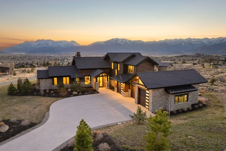 View of front of home with stone siding, concrete driveway, a chimney, and a mountain view