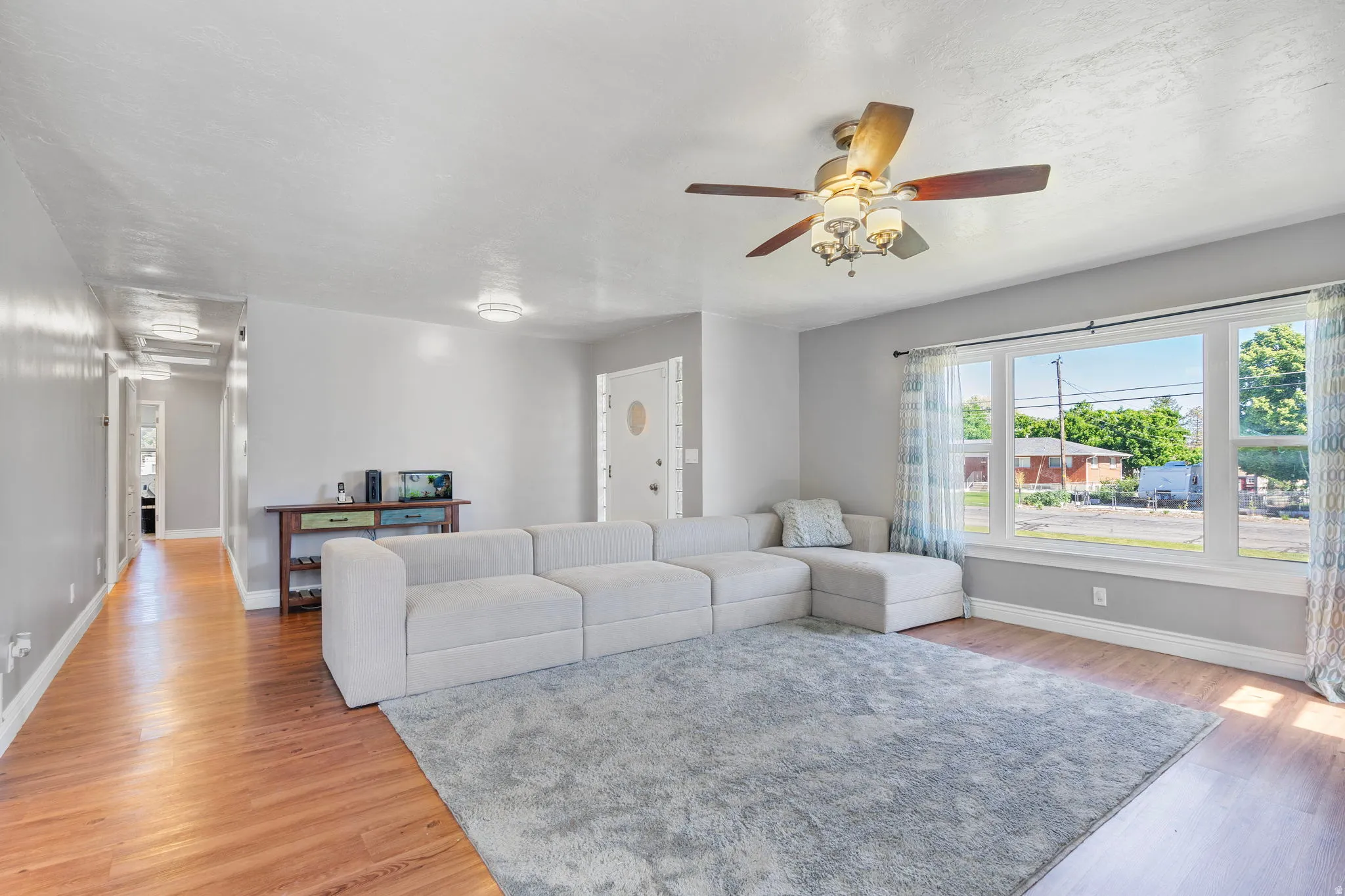 Living area with a ceiling fan and light wood-style floors