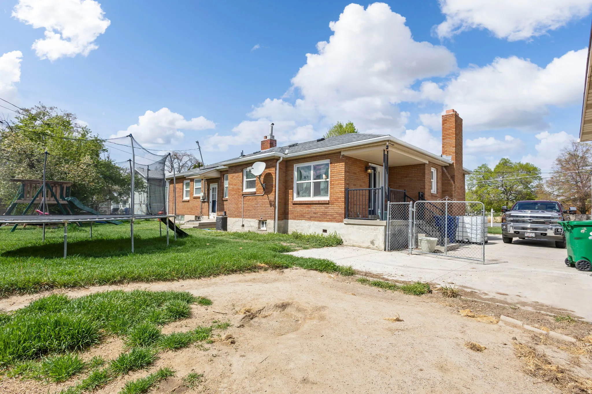View of front of house with a chimney, brick siding, a trampoline, and a playground