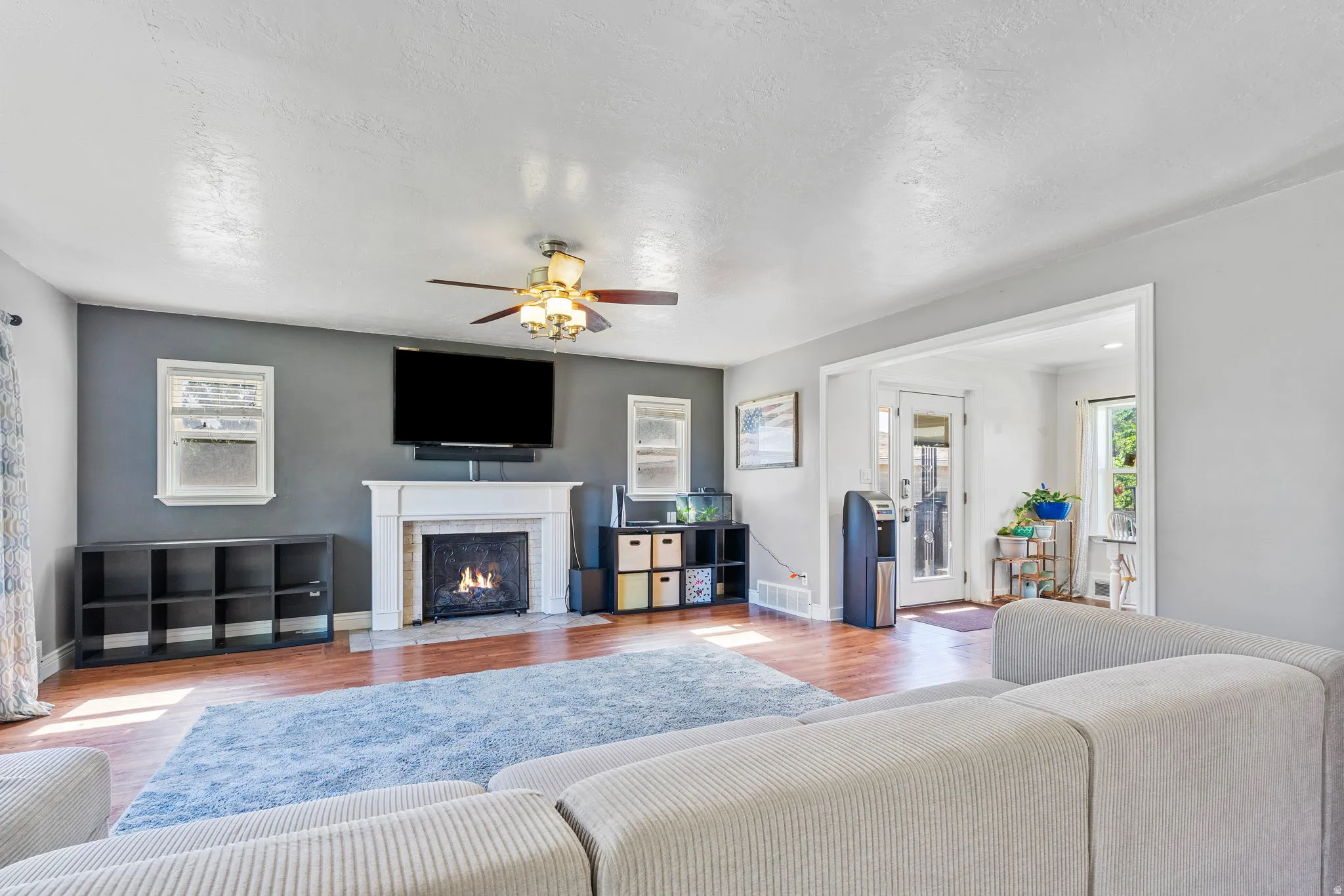 Living area with wood finished floors, a fireplace with flush hearth, and a ceiling fan