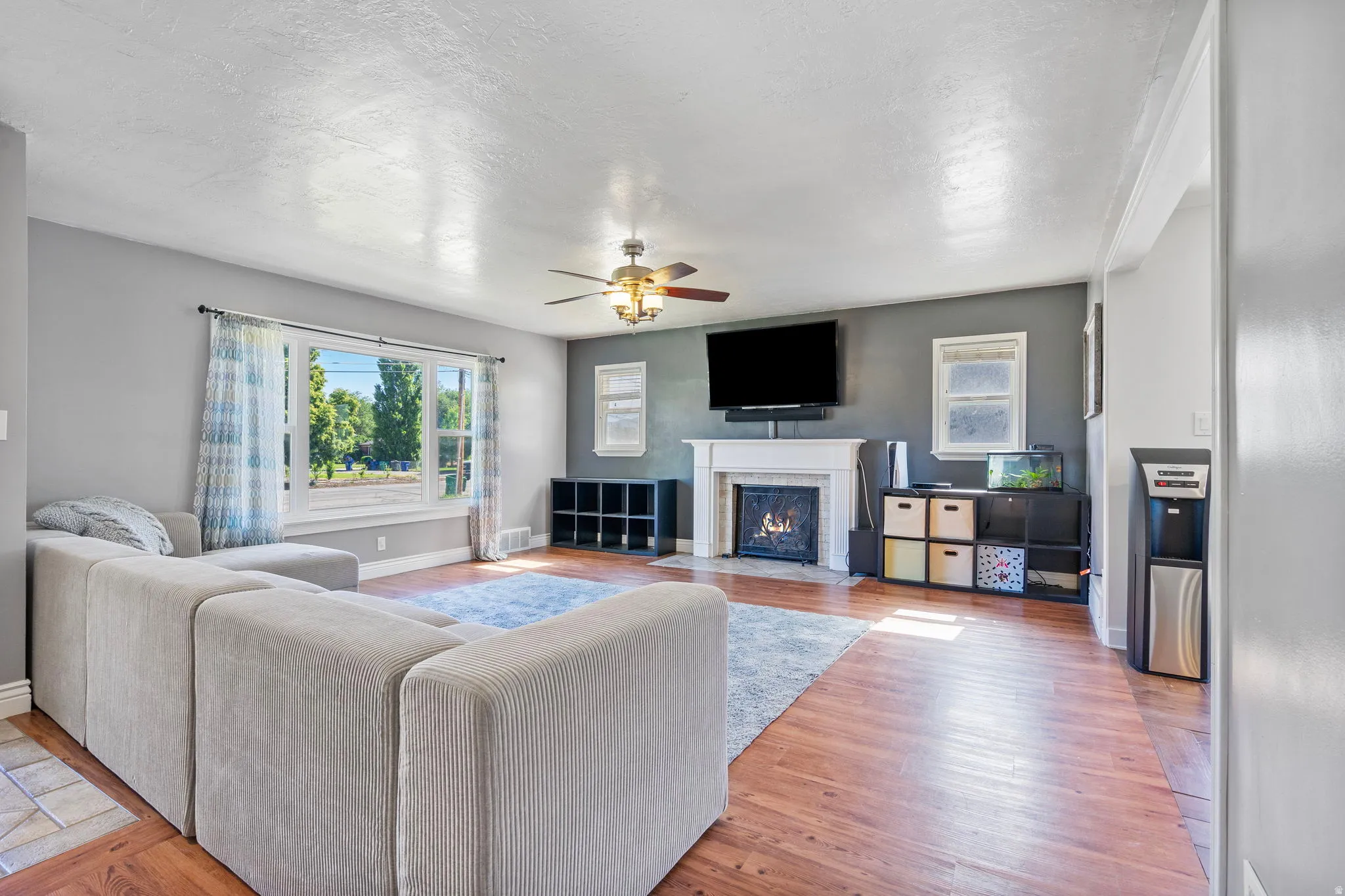 Living area with a ceiling fan, a fireplace with flush hearth, and light wood-type flooring