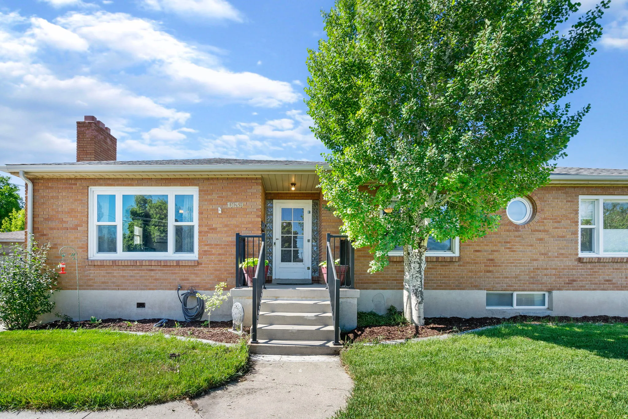 View of front of house with a front yard, brick siding, and a chimney