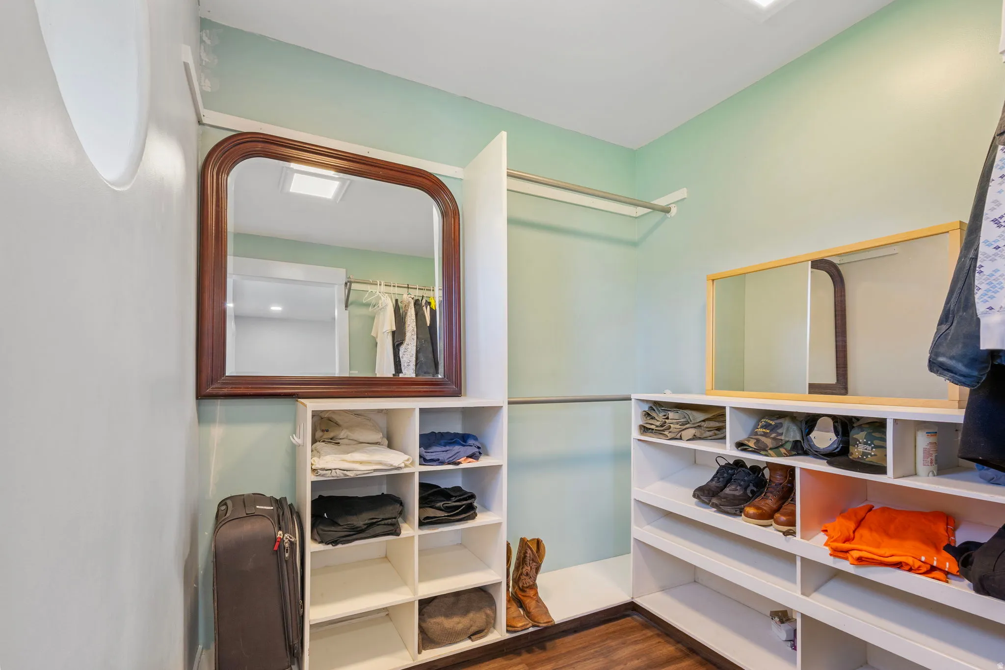 Walk in closet with dark wood-style floors