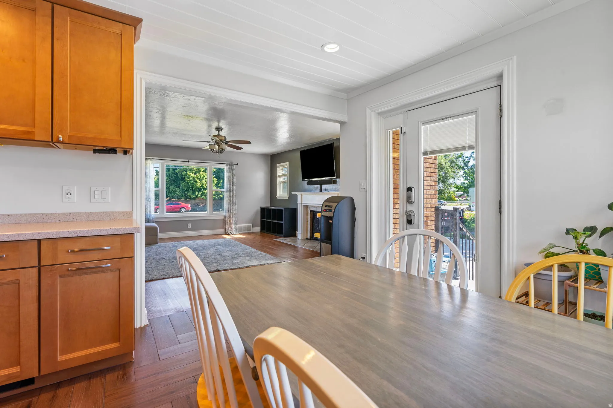 Dining area featuring dark wood finished floors, a fireplace with flush hearth, a ceiling fan, crown molding, and recessed lighting