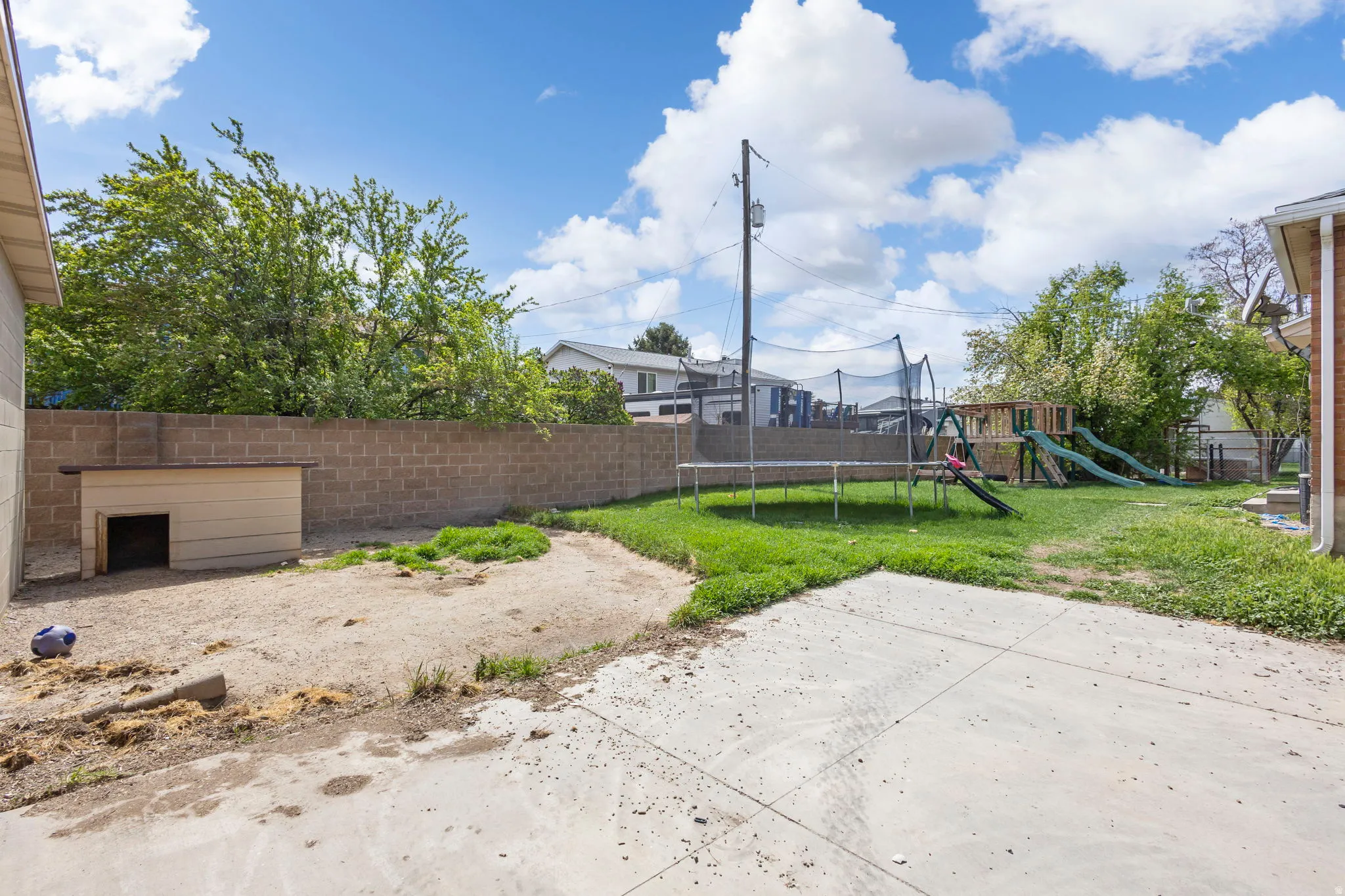 Fenced backyard with a trampoline and a playground