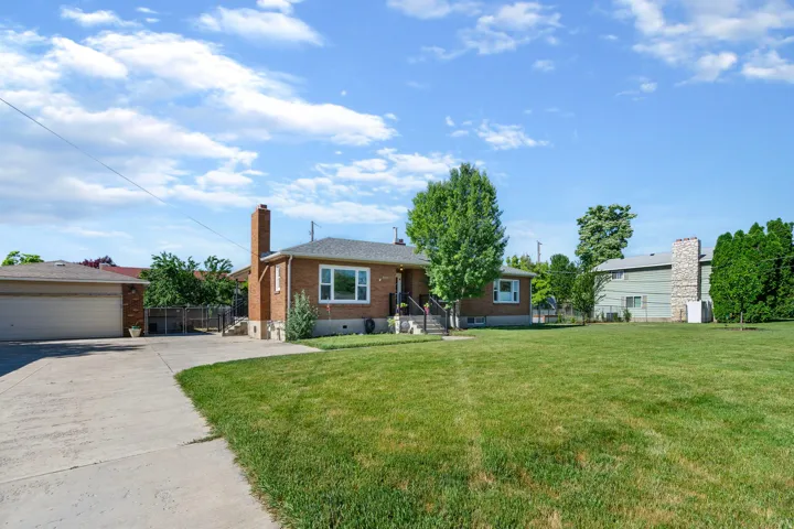 View of front of house with brick siding, a detached garage, and a chimney