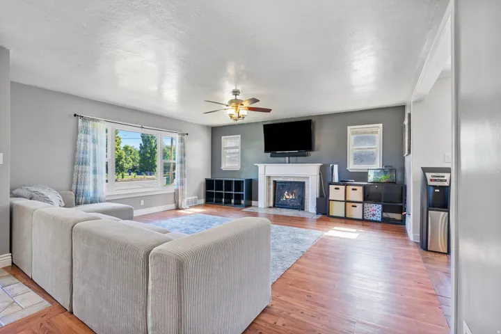 Living area with a ceiling fan, a fireplace with flush hearth, and light wood-type flooring