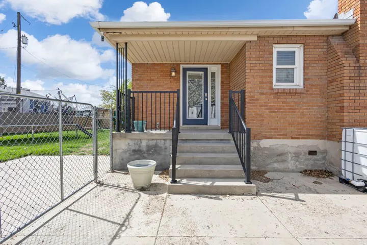 Entrance to property with a gate, brick siding, and a porch