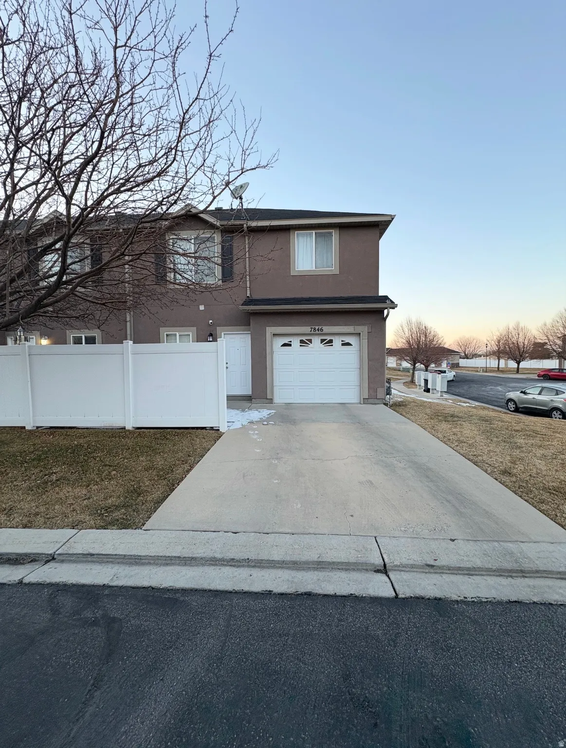 Traditional-style house with an attached garage, concrete driveway, and stucco siding