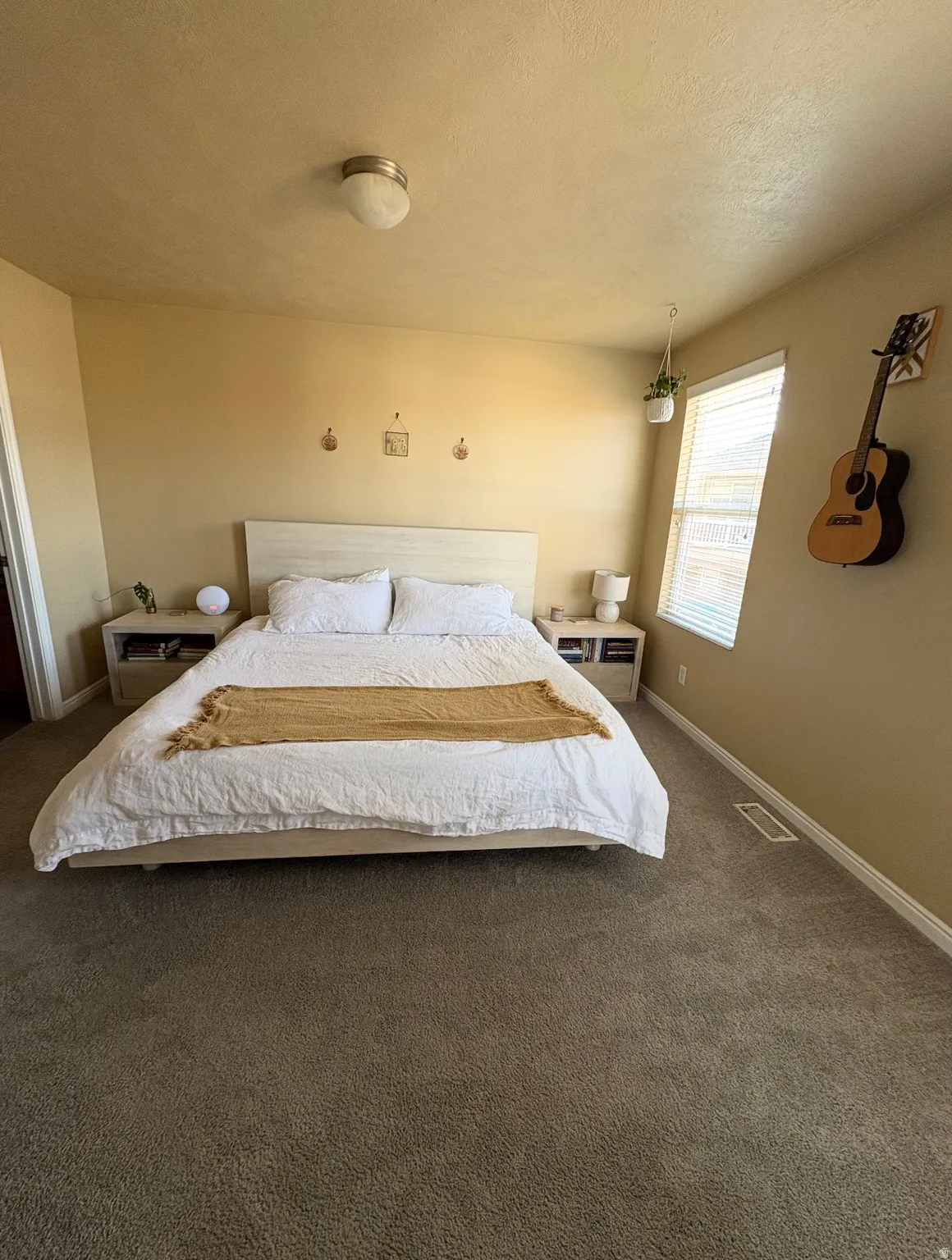 Carpeted bedroom with a textured ceiling and baseboards