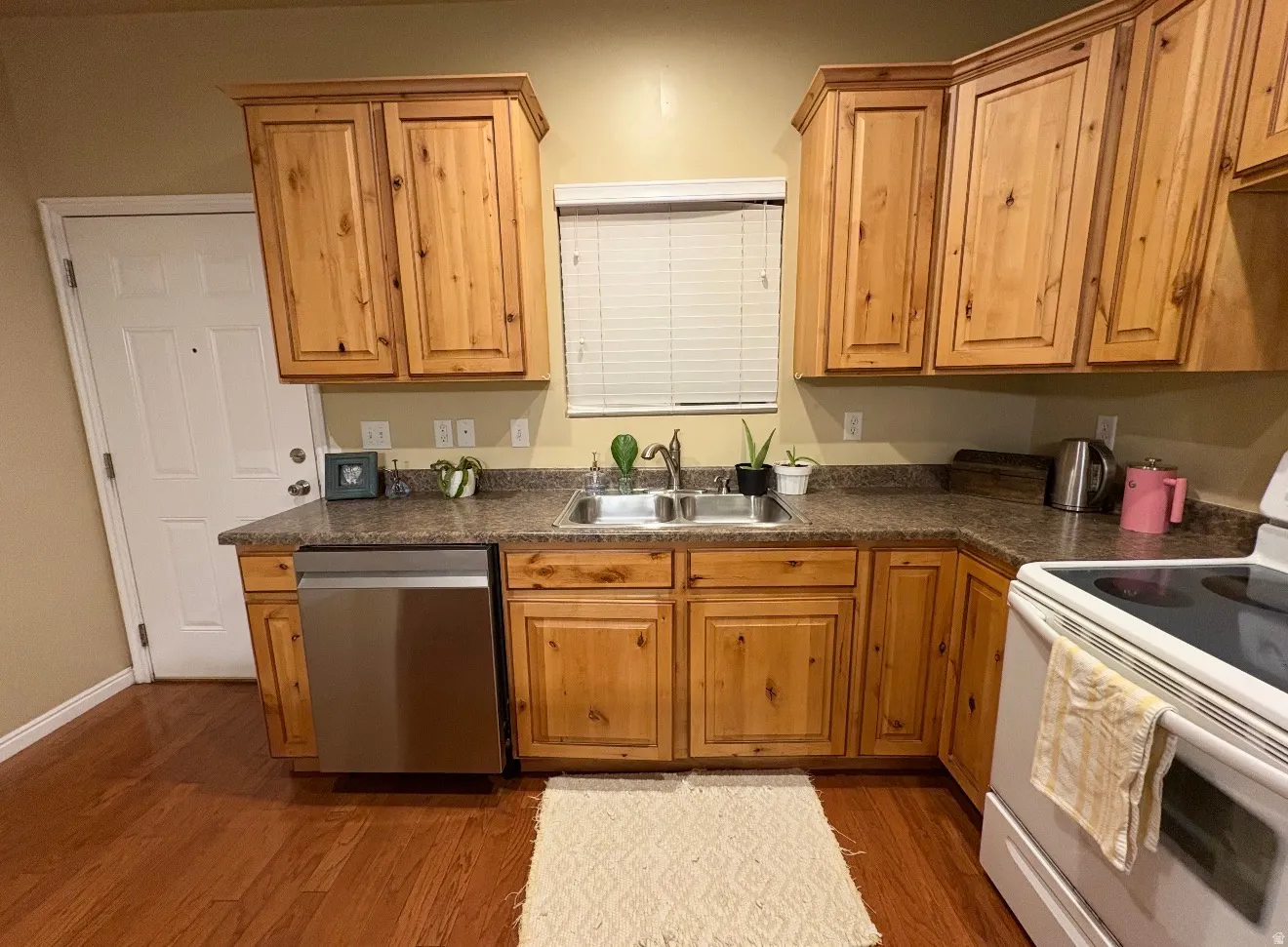 Kitchen featuring electric stove, dark countertops, stainless steel dishwasher, dark wood finished floors, and wood finish cabinets