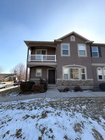 View of front facade featuring stucco siding, a balcony, and a porch