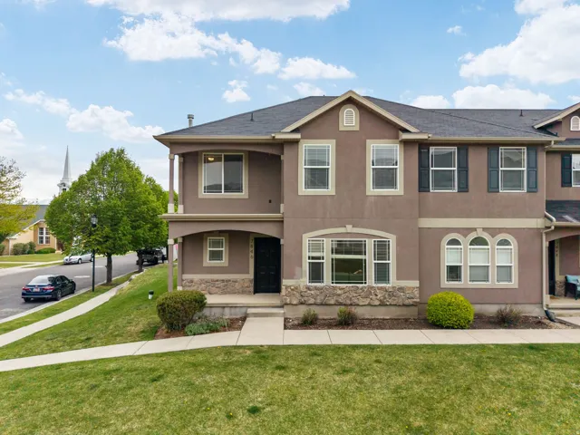 View of front of house featuring a front lawn, stucco siding, a porch, and stone siding