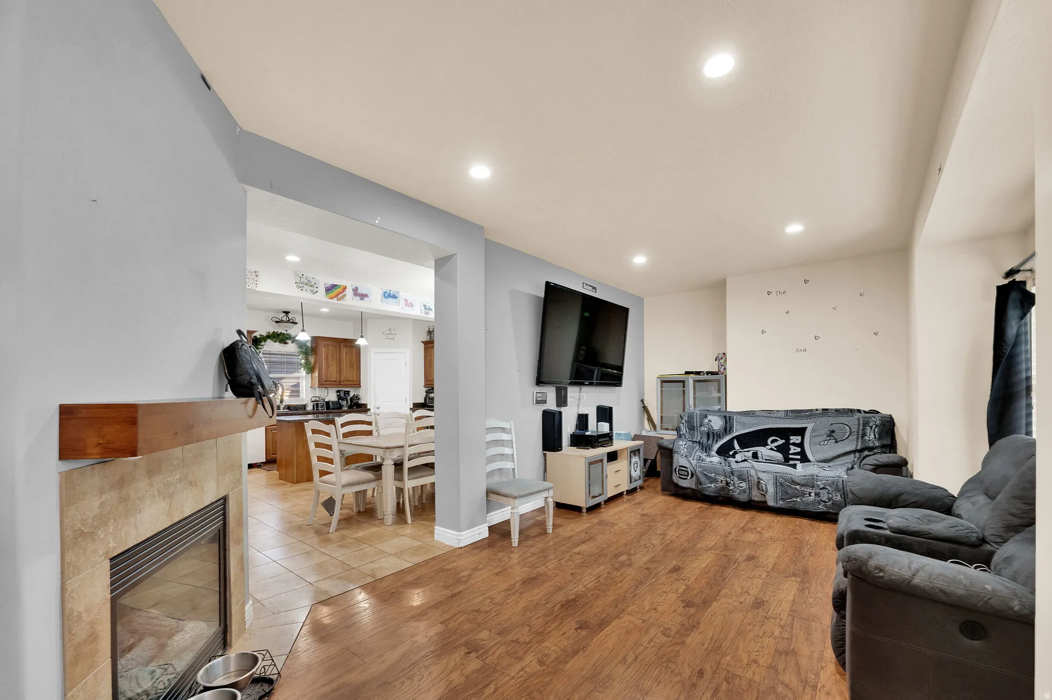 Living area with recessed lighting, a tile fireplace, and light wood-style flooring