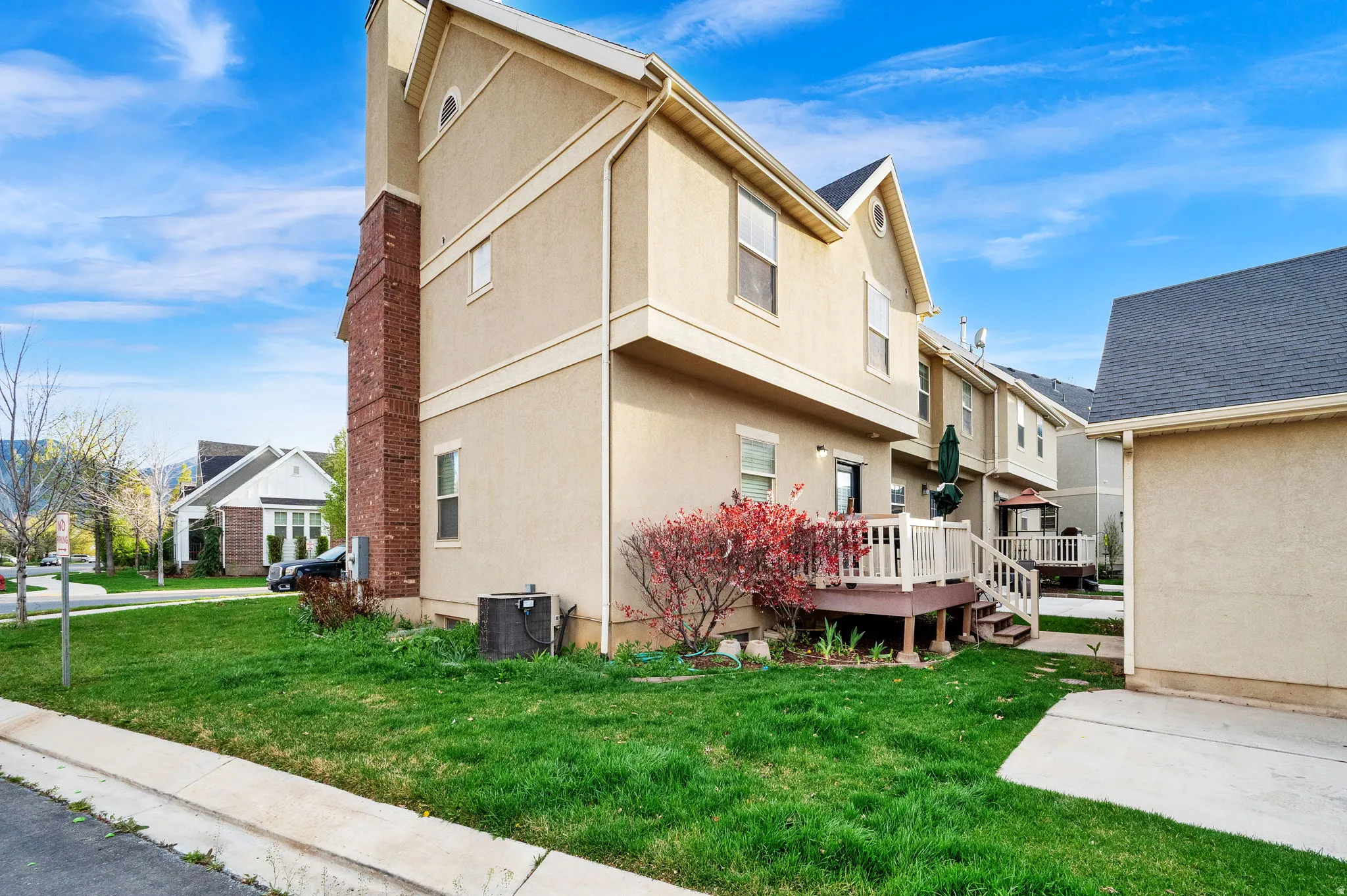 Rear view of property featuring a lawn, stucco siding, and a wooden deck