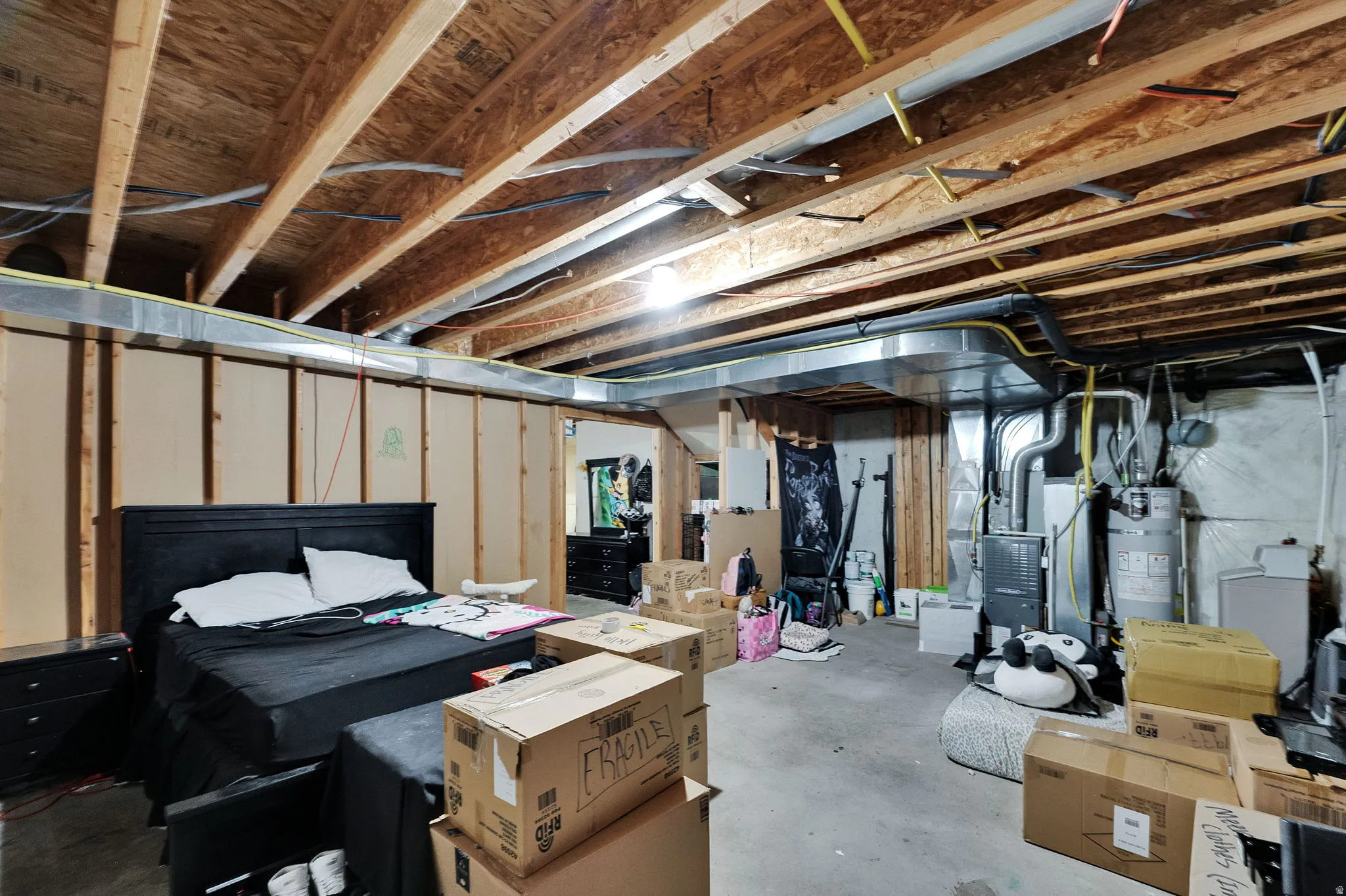 Unfinished below grade area featuring water heater and heating unit