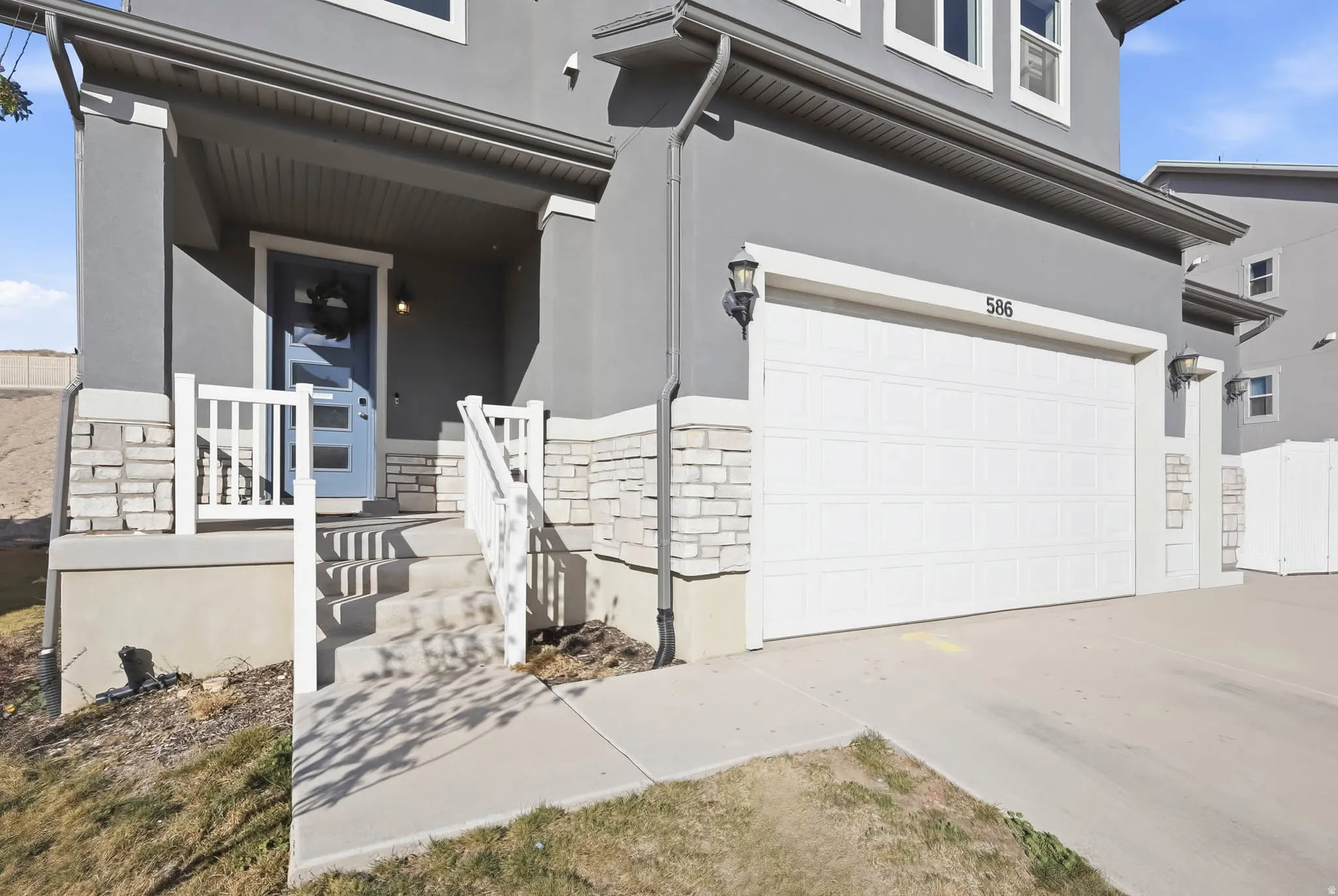 View of front of property with an attached 3-car garage, stone siding, stucco siding, concrete driveway, and a porch