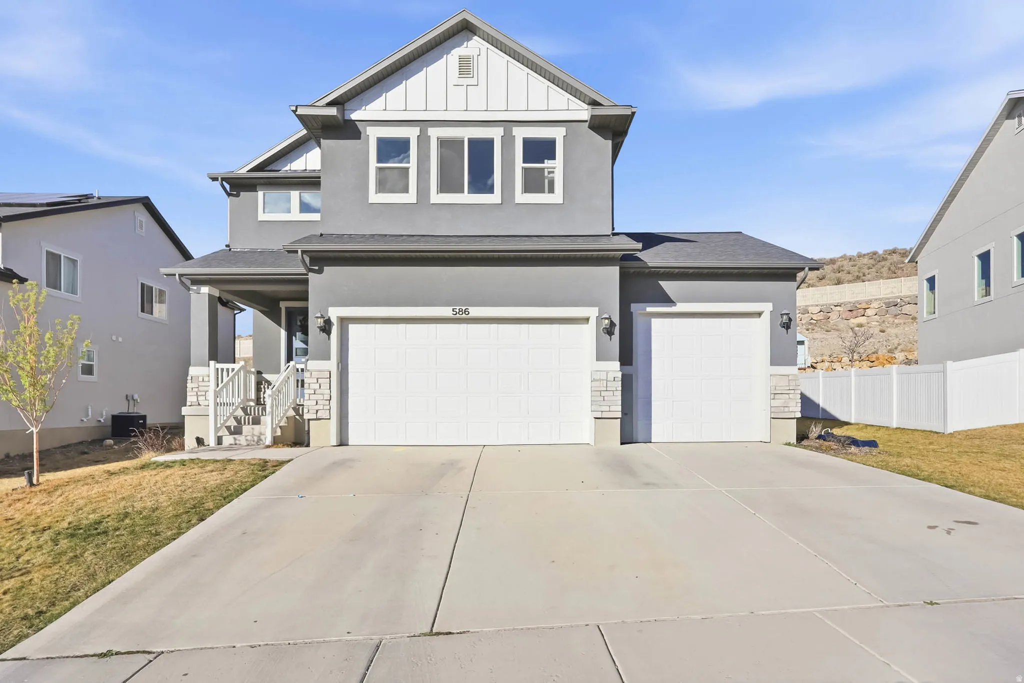 View of front of property with concrete driveway, an attached garage, stucco siding, board and batten siding, and stone siding
