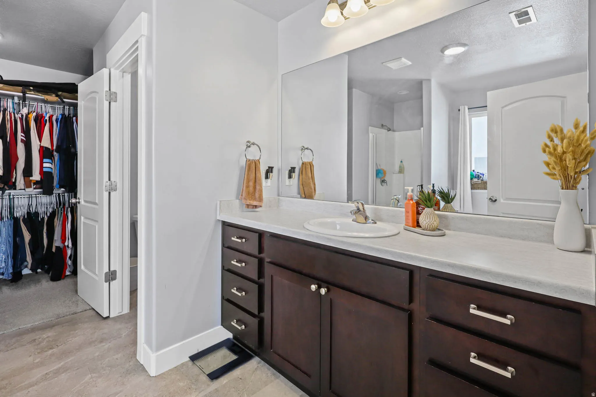 Primary Bathroom with a stall shower, a walk in closet, vanity, and a textured ceiling